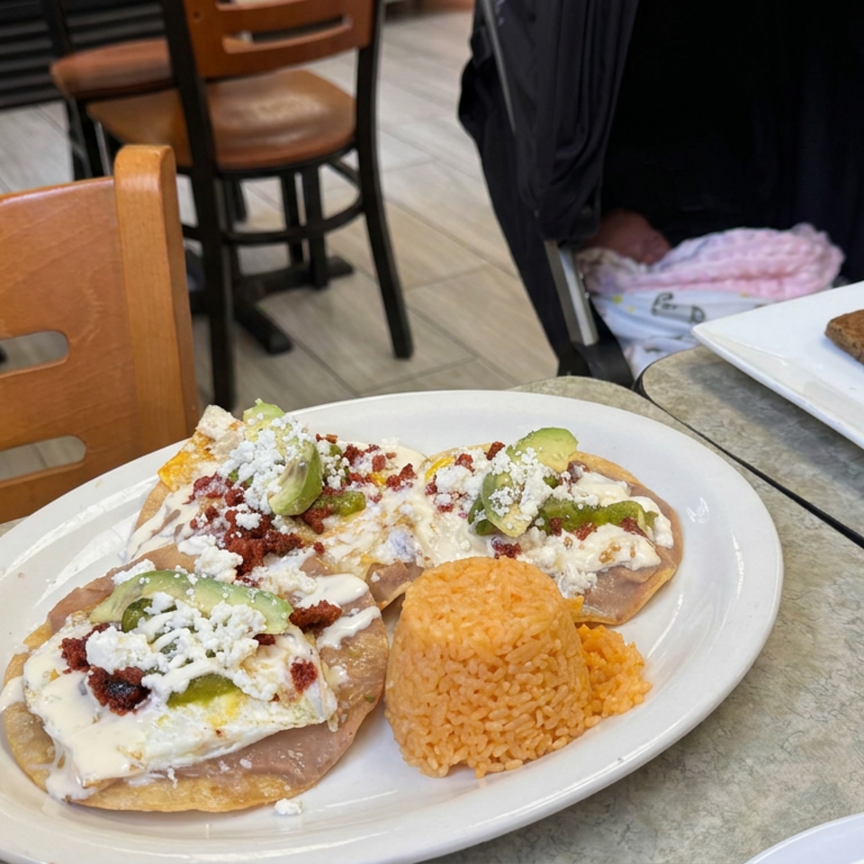 Mexican restaurant plate with two tostadas topped with beans, cheese, avocado, and meat, served with orange rice and a brownie.